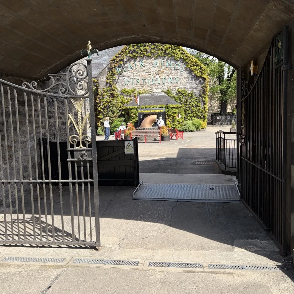 View through the dark archway onto the sunny, flowering courtyard of Blair Athol