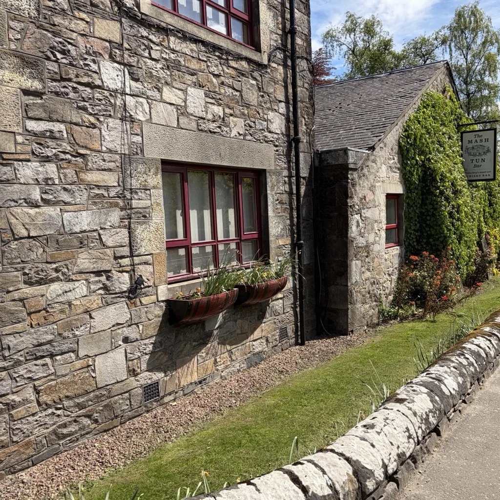 Detail of the old stone walls of Blair Athol with red-framed windows and flower boxes