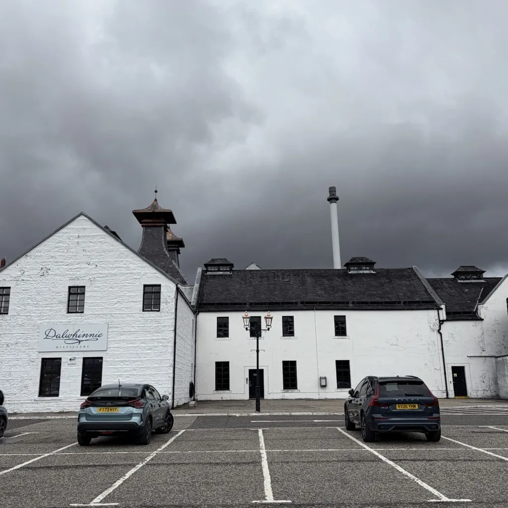 The white buildings of Dalwhinnie Distillery with a pagoda roof in the Scottish Highlands