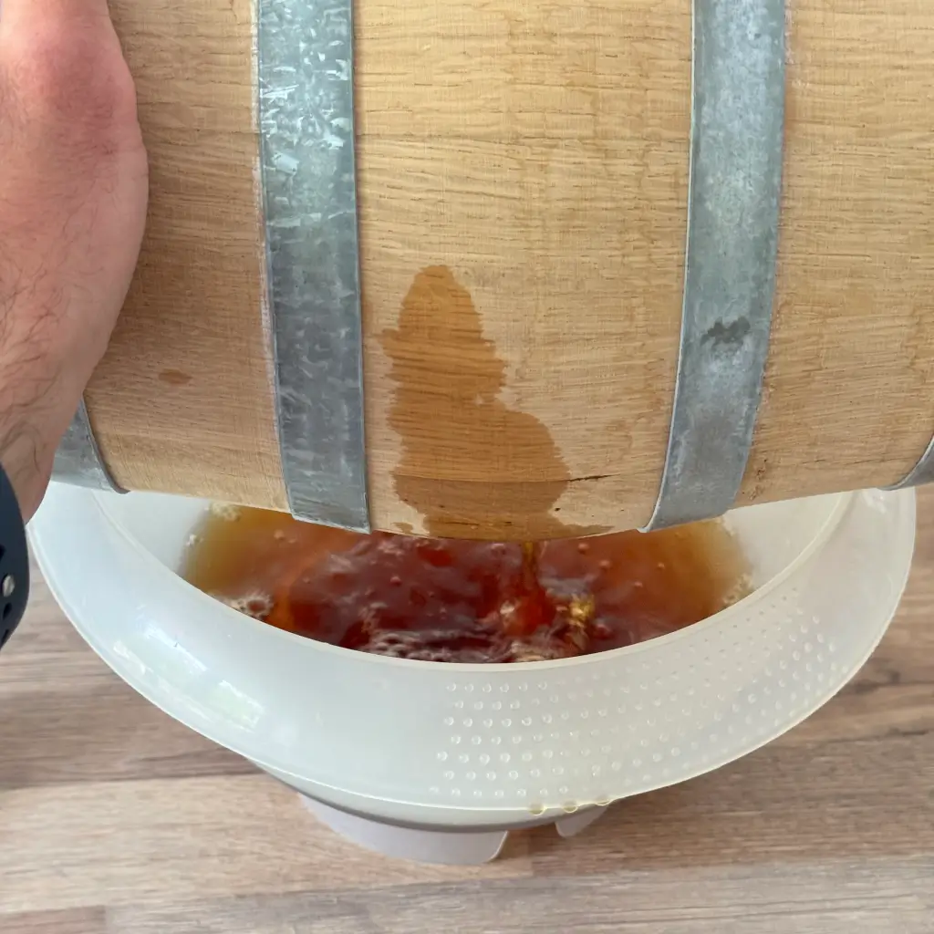 The small oak cask being emptied into a bowl, the spirit running out