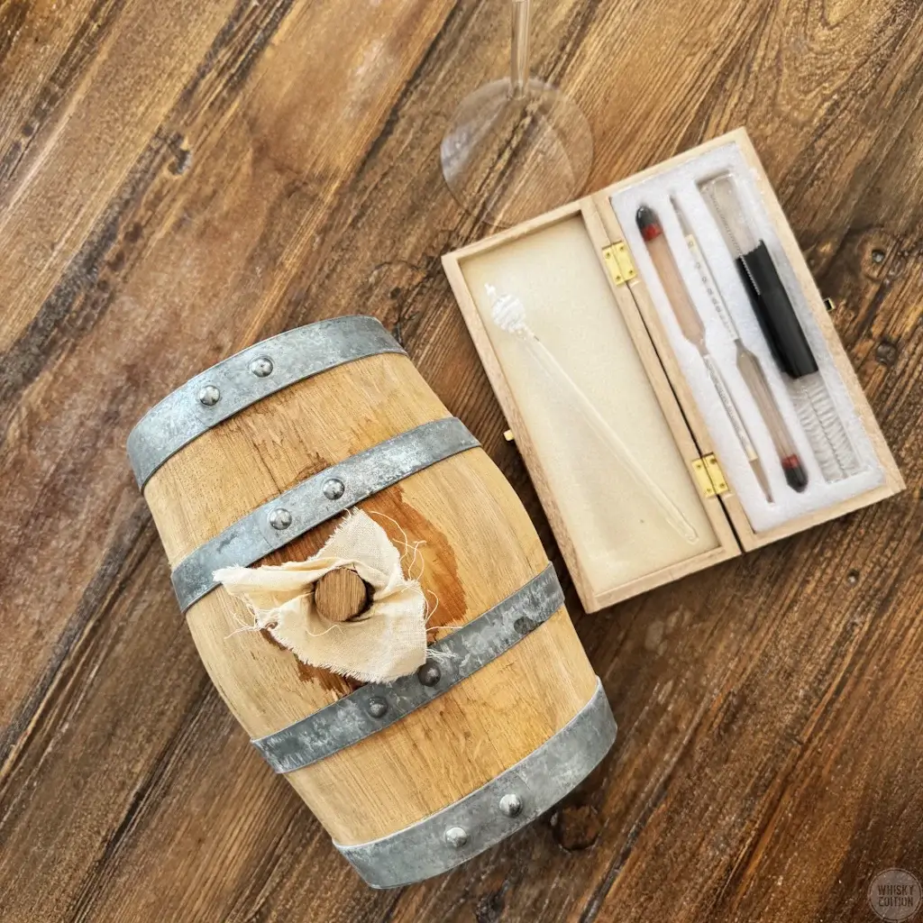 Small 3-litre oak cask next to a hydrometer set on a wooden table
