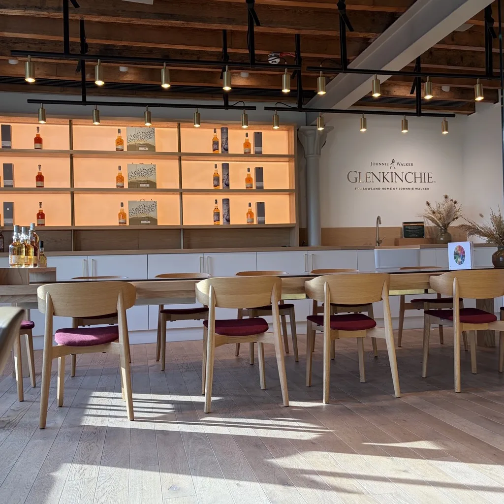 The modern tasting room at Glenkinchie with illuminated shelves and the Johnnie Walker Glenkinchie lettering on the wall